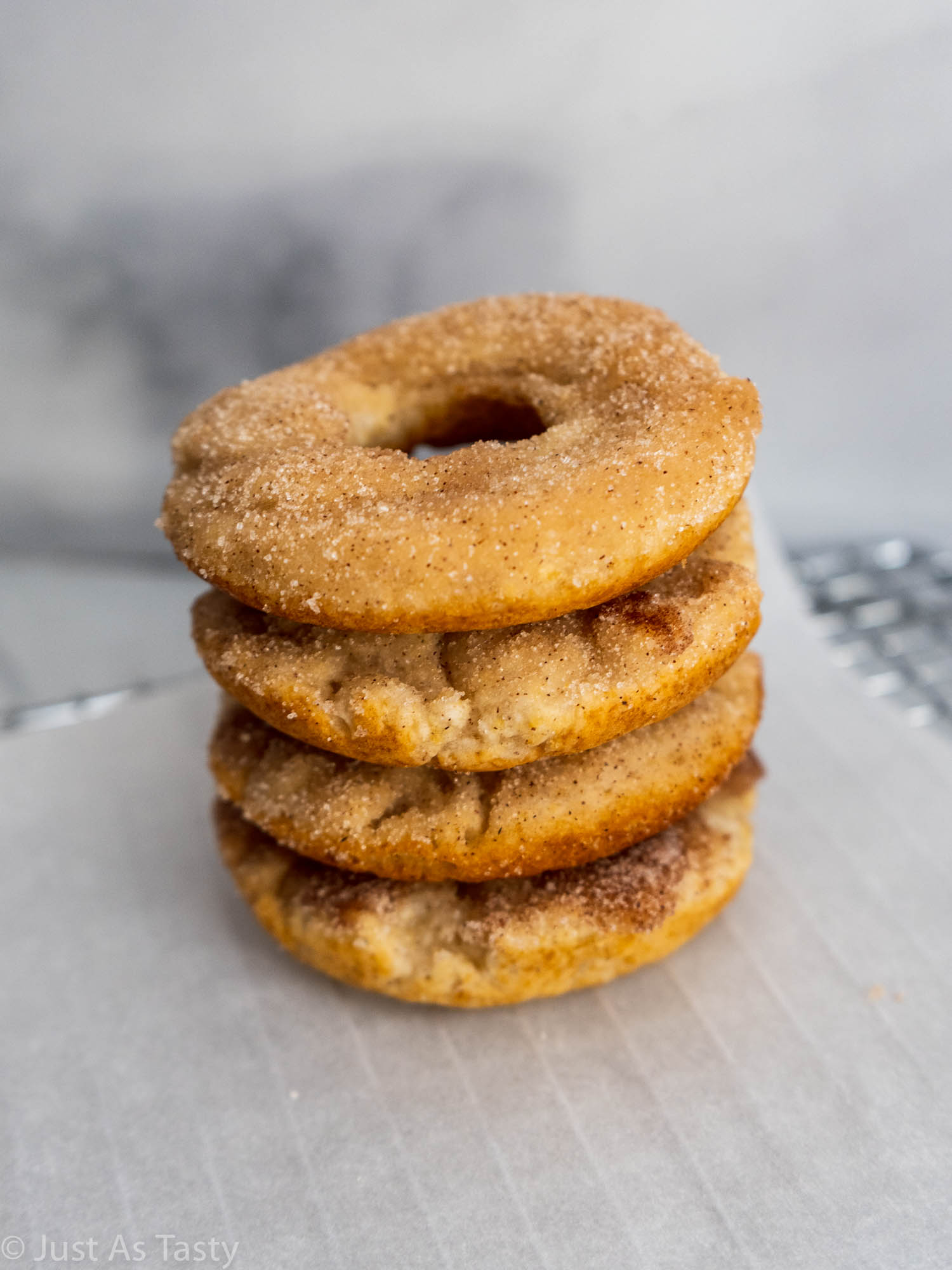 Stack of cinnamon donuts on white parchment paper.