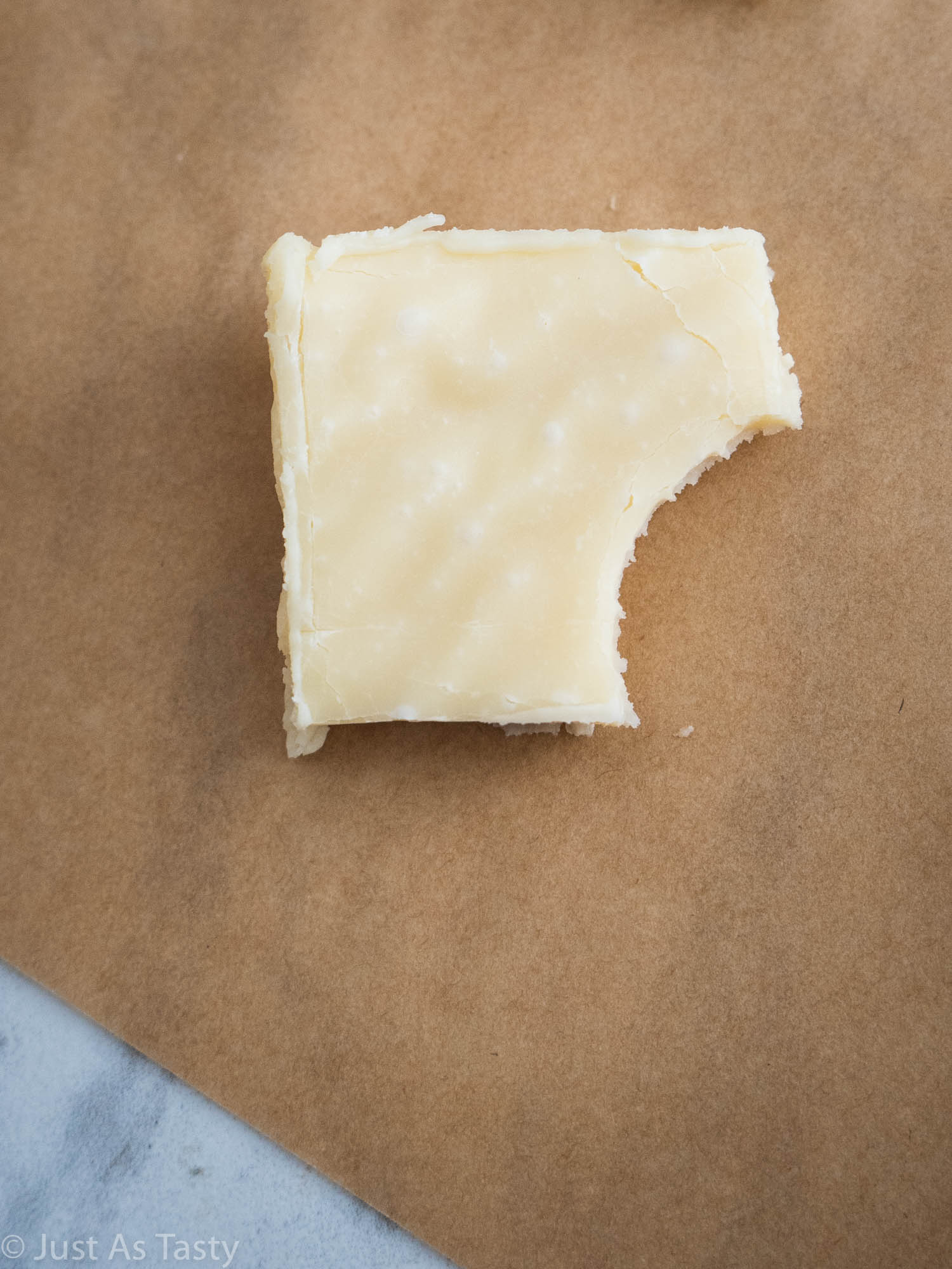 Maple fudge with a bite taken out of it on brown parchment paper.