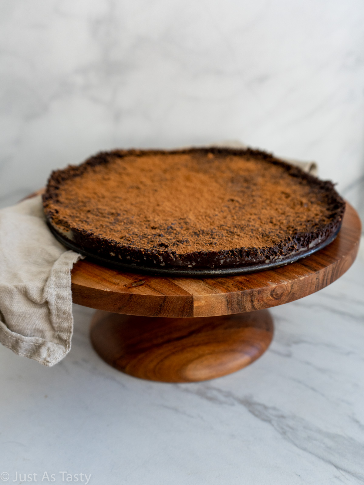 Flourless chocolate cake dusted with cocoa powder on a brown cake stand.