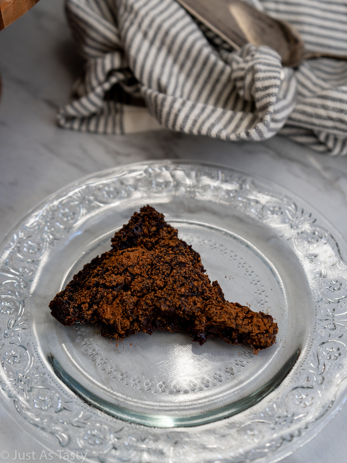 Slice of flourless chocolate cake on a glass plate.