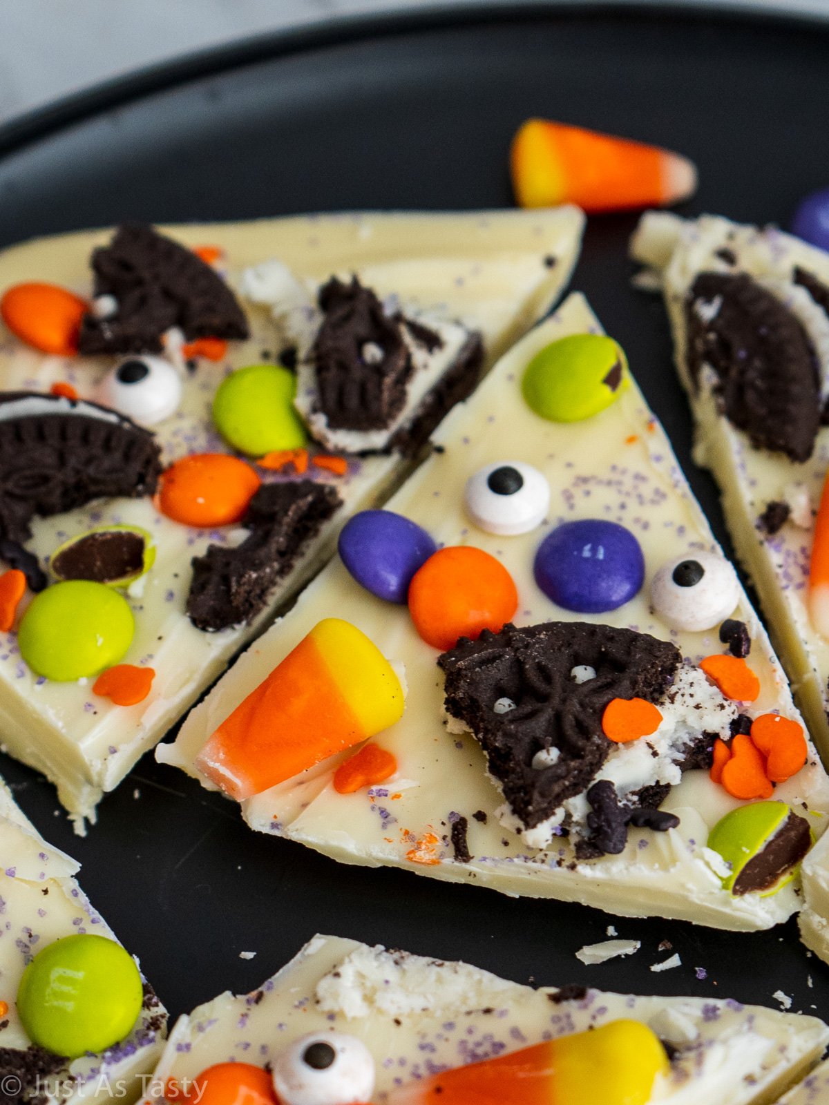 Close-up of a piece of white chocolate bark topped with Halloween candy and sprinkles. 