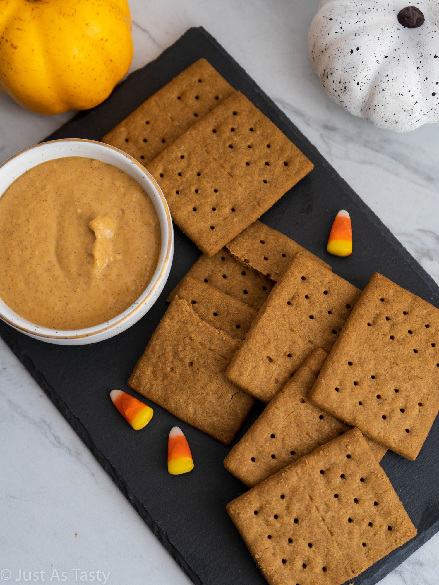 Pumpkin dip in a white bowl surrounded by graham crackers. 