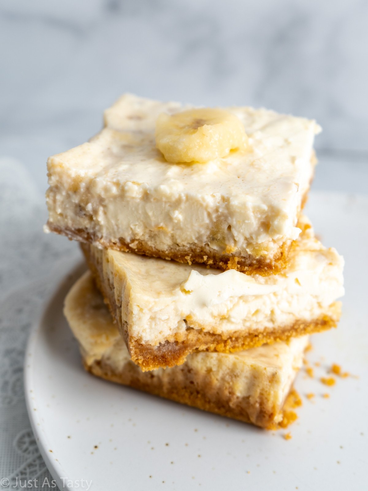 Stack of three banana pudding cheesecake squares on a white plate.