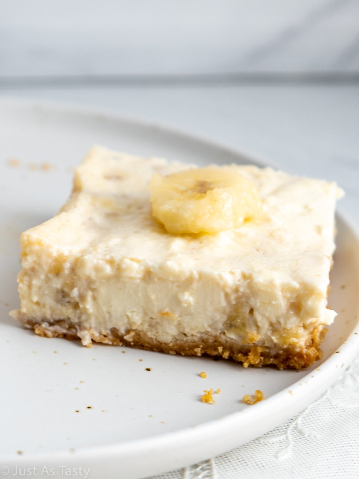 Close-up of a banana pudding cheesecake square on a white plate.