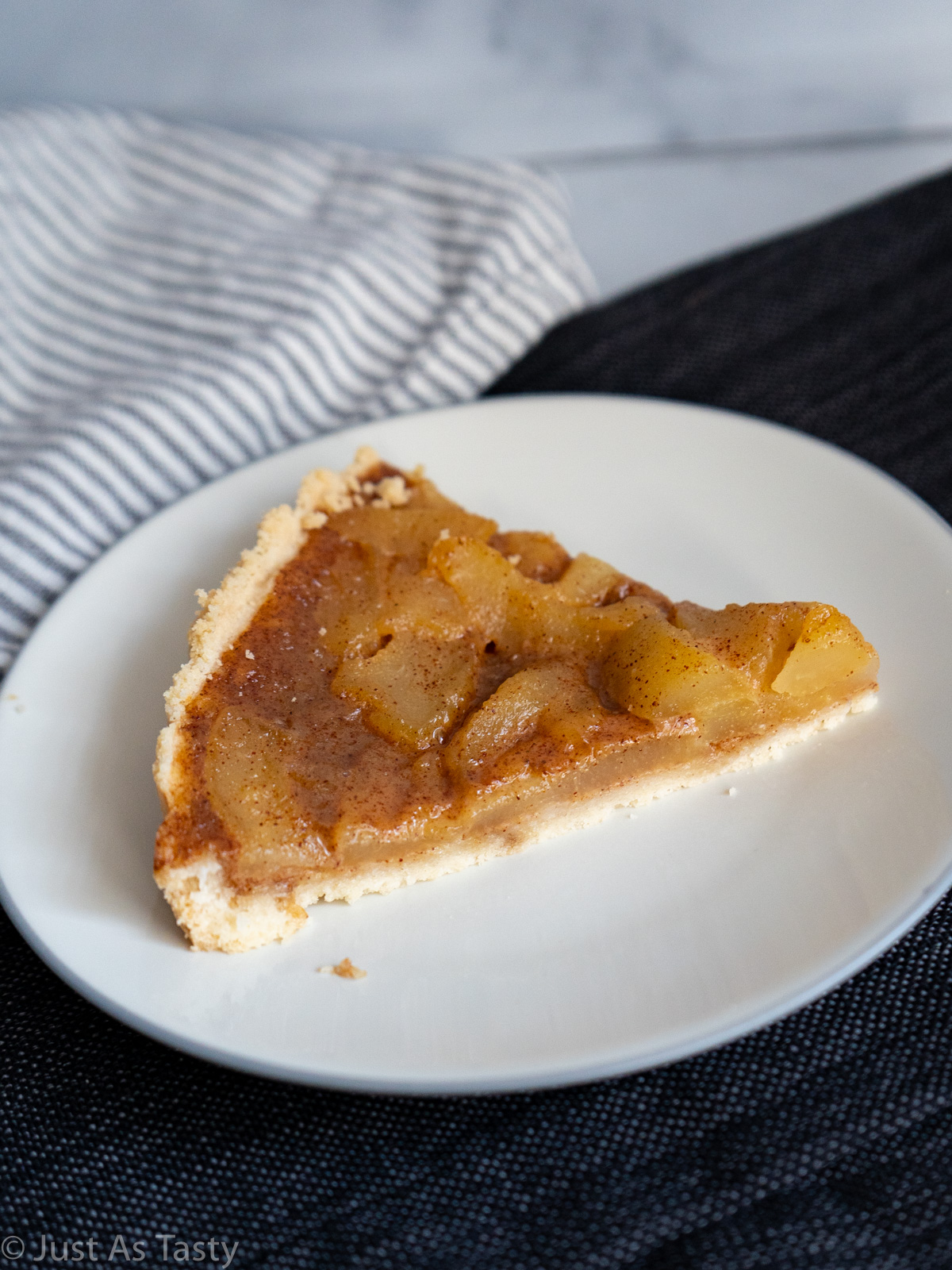 Slice of pear tart on a white plate.