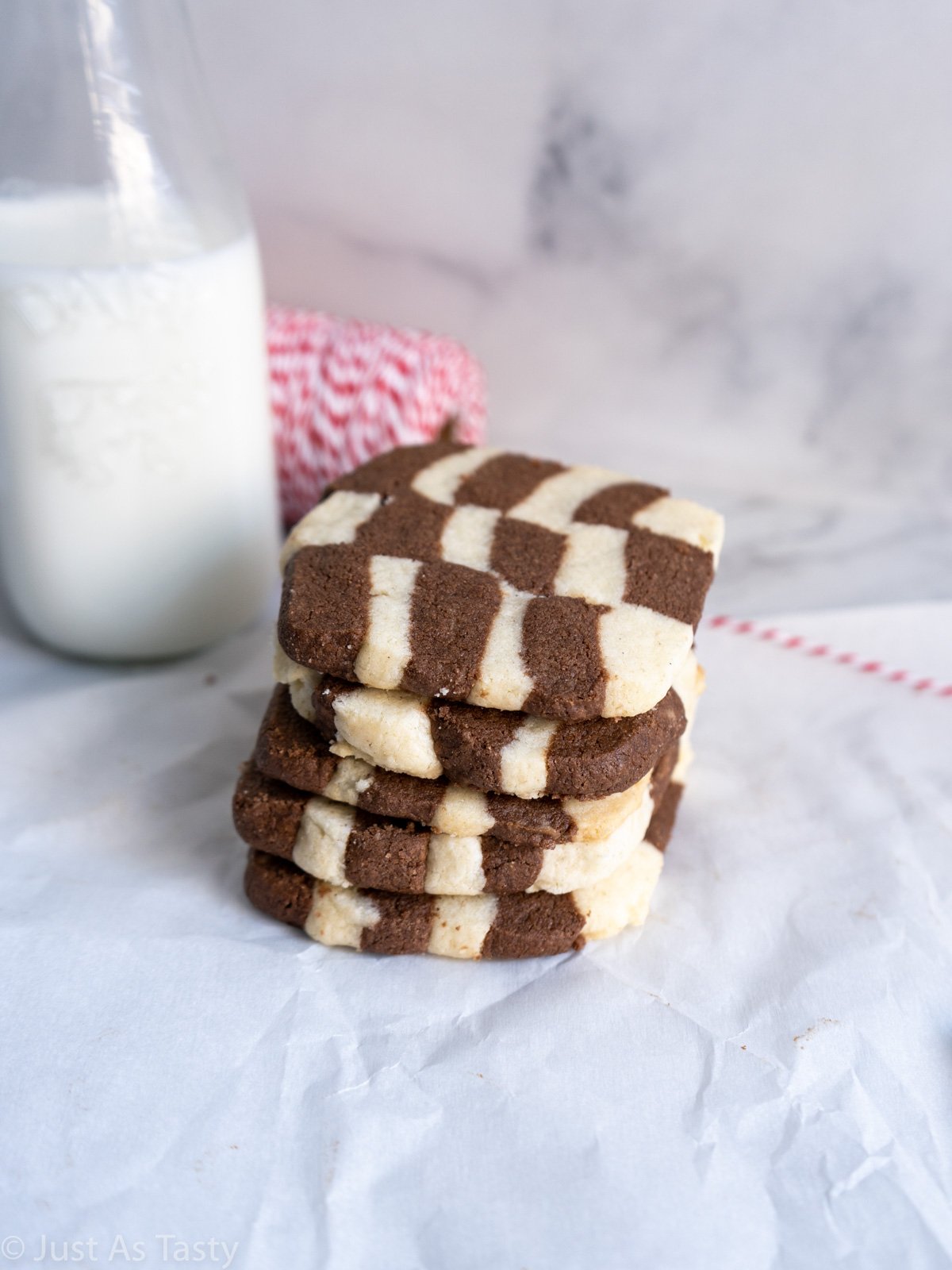 Stack of checkerboard icebox cookies on white parchment paper.
