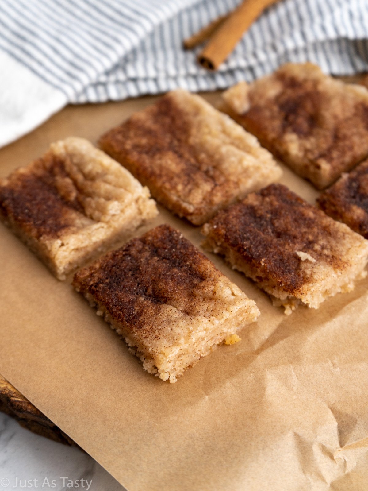 Square bars topped with cinnamon on brown parchment paper.