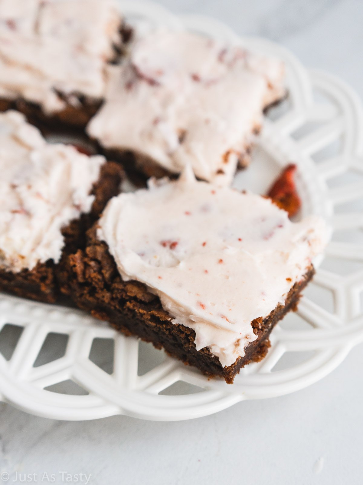 Frosted strawberry brownies on a plate.