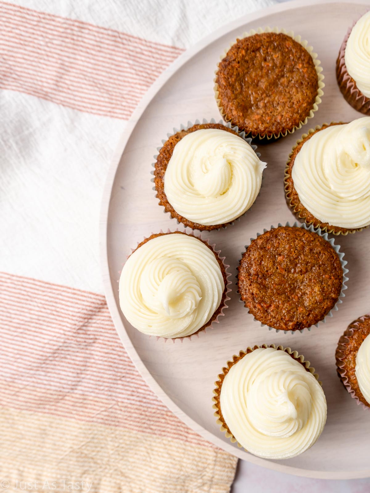 Frosted and unfrosted carrot cake cupcakes on a plate. 