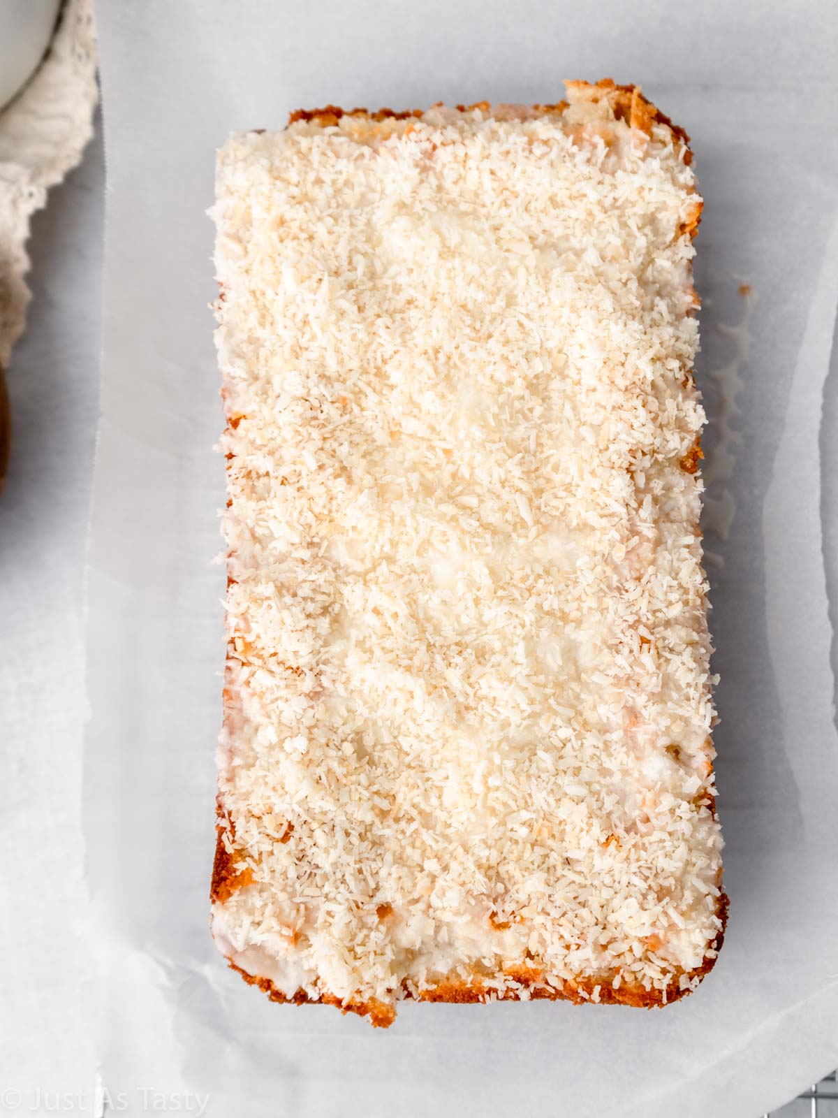 Loaf cake topped with icing and shredded coconut.