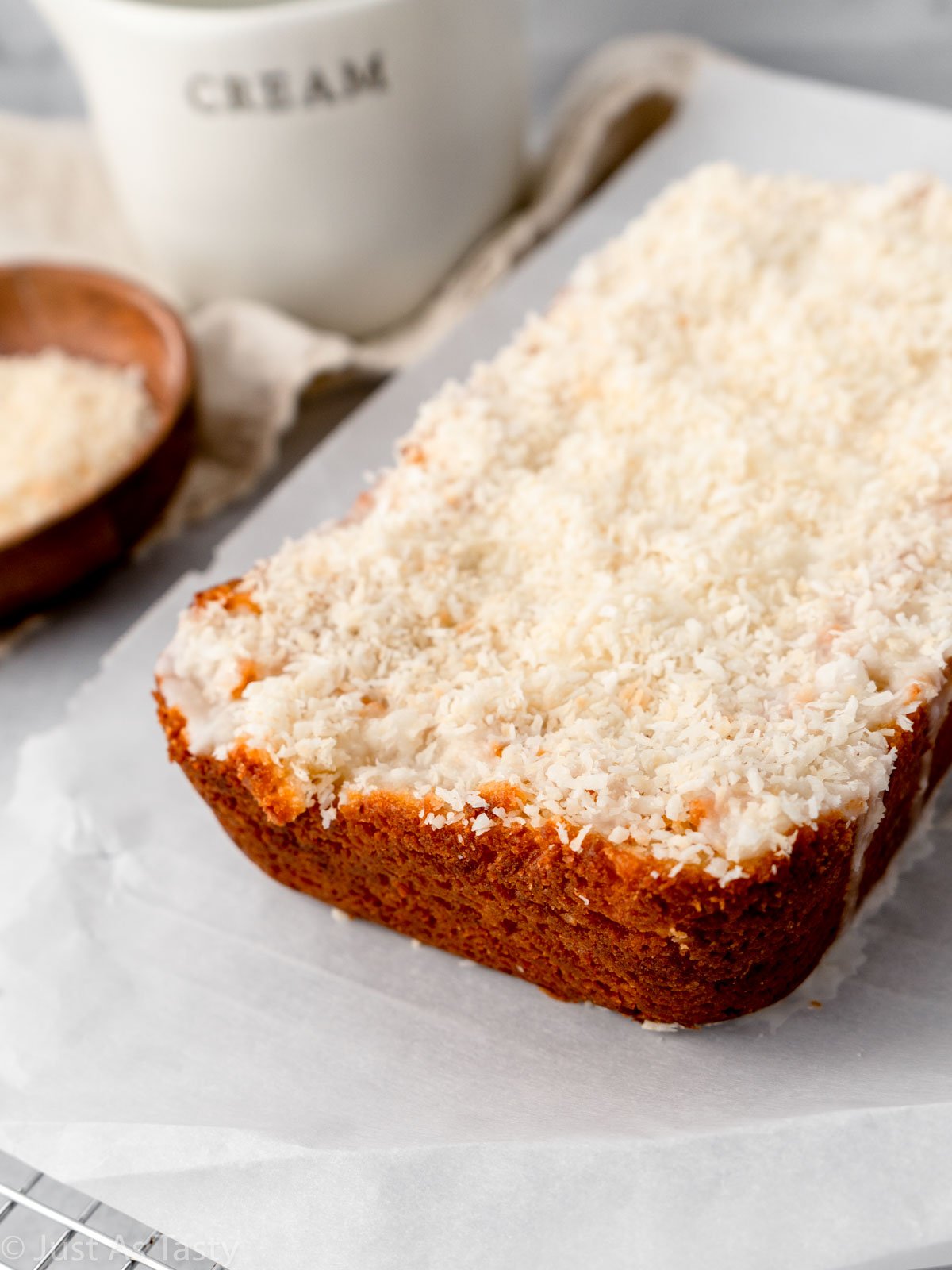 Loaf cake topped with icing and shredded coconut.