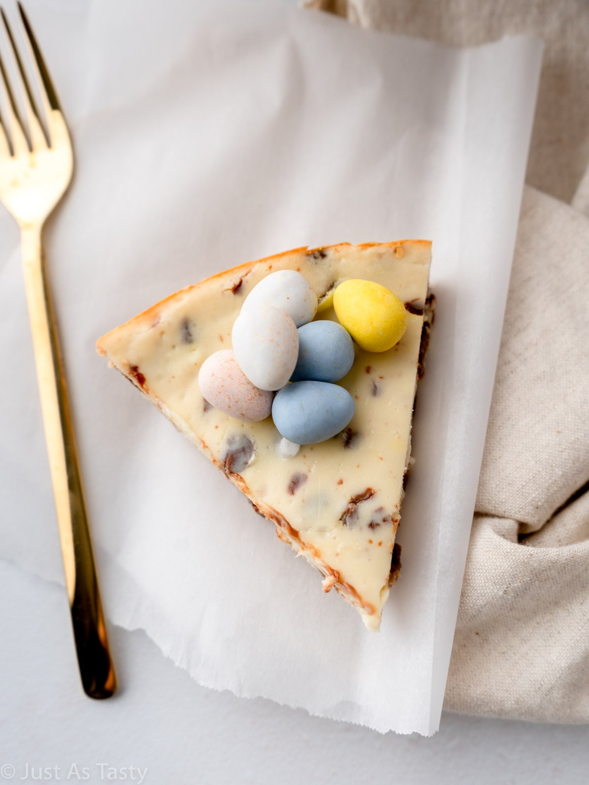 Slice of Easter egg cheesecake topped with pastel mini chocolate eggs.