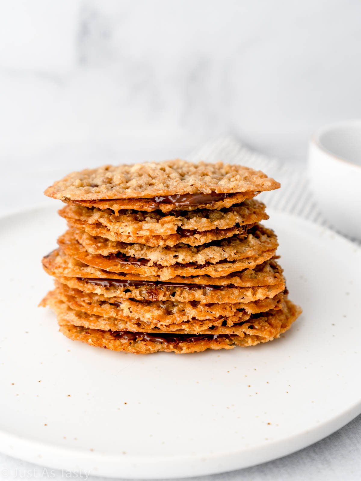 Stack of oatmeal lace cookies with melted chocolate.