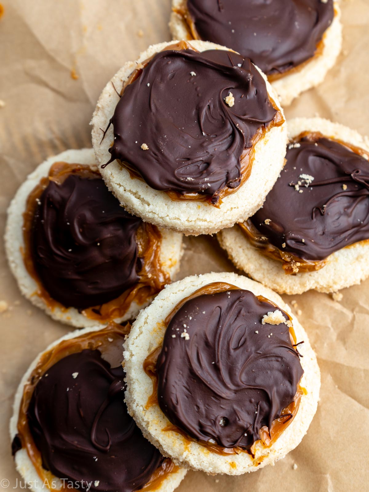 Pile of gluten free shortbread cookies topped with chocolate and caramel.