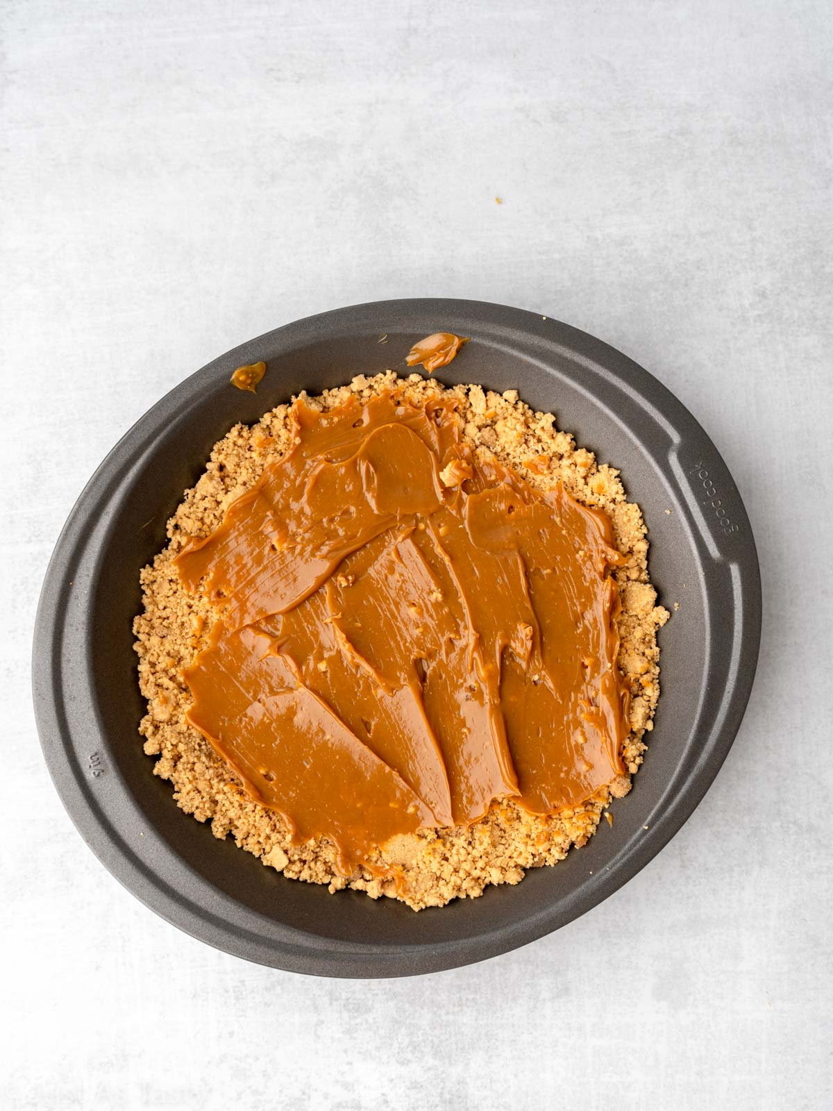 Graham cracker crust topped with dulce de leche in a pie plate. 