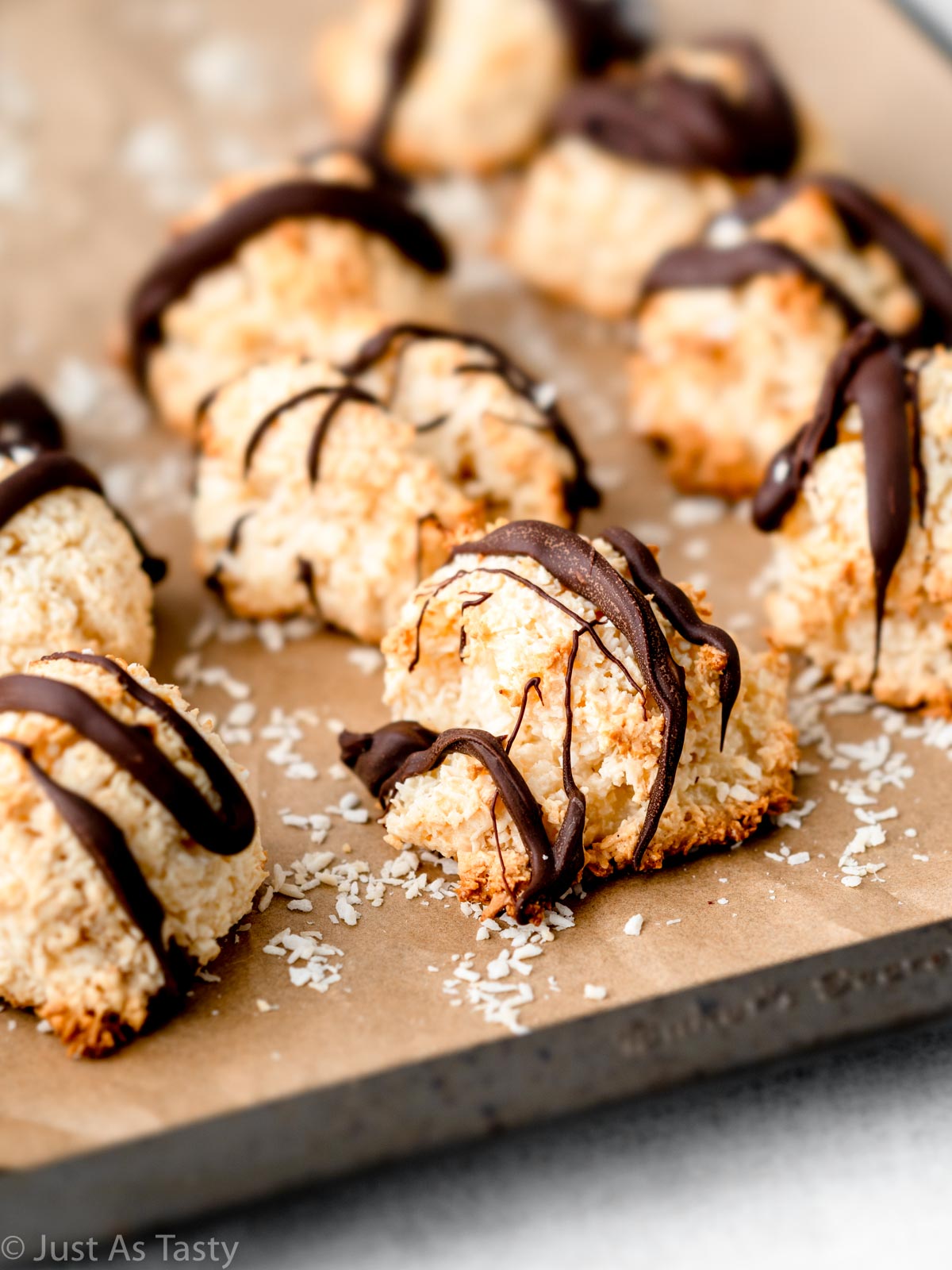 Coconut macaroons drizzled with chocolate on a lined baking sheet. 