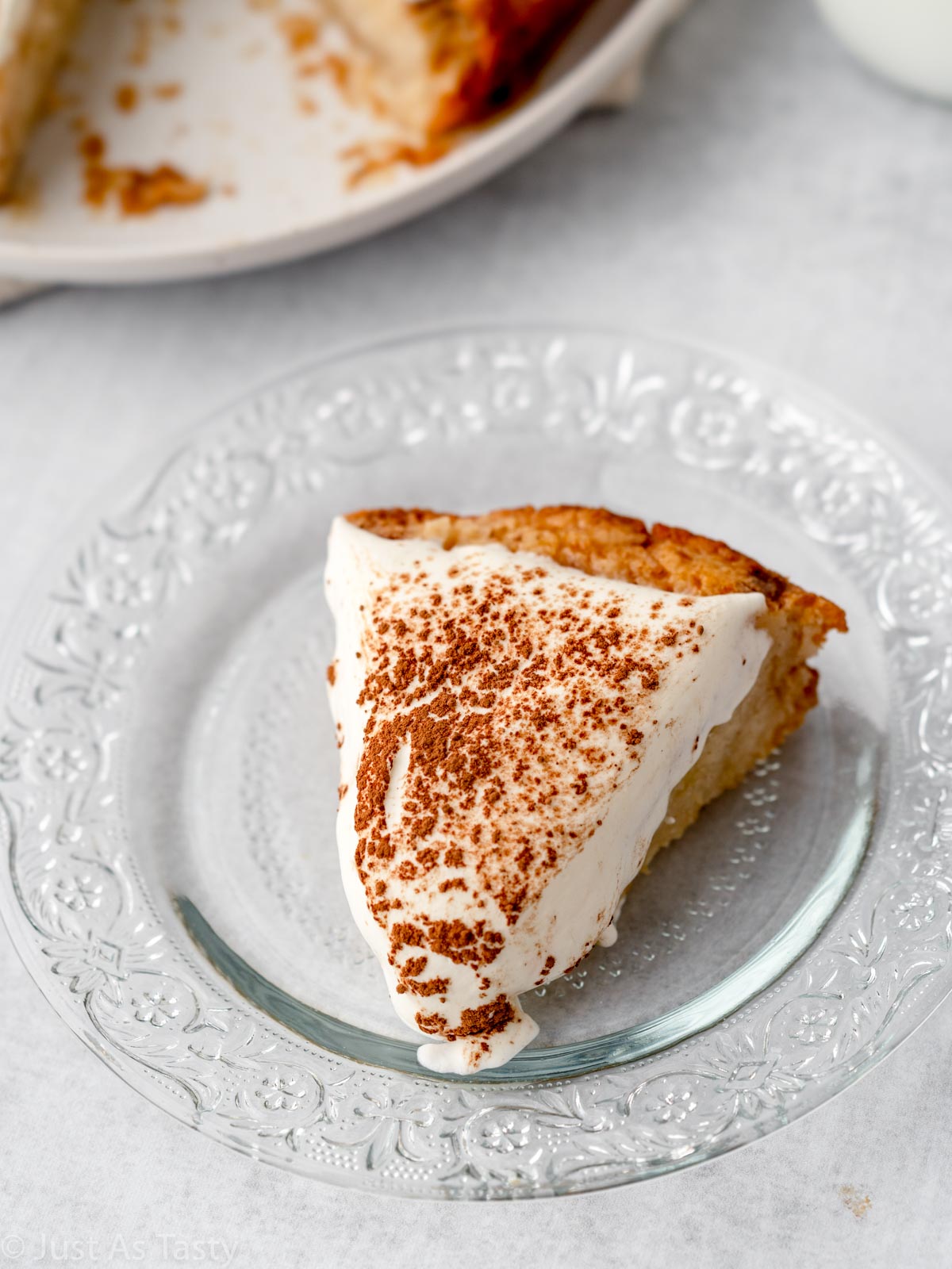 Slice of tres leches cake on a glass plate. 