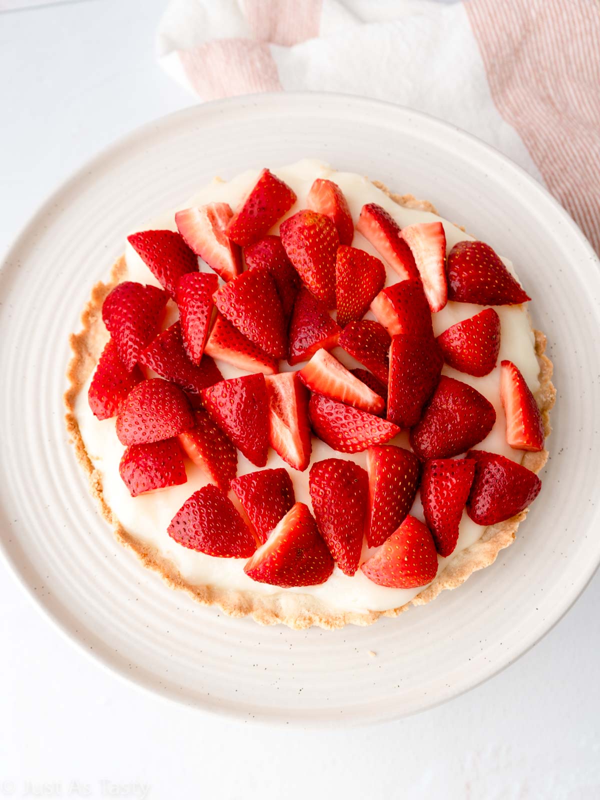 Strawberry custard tart on a cake stand.