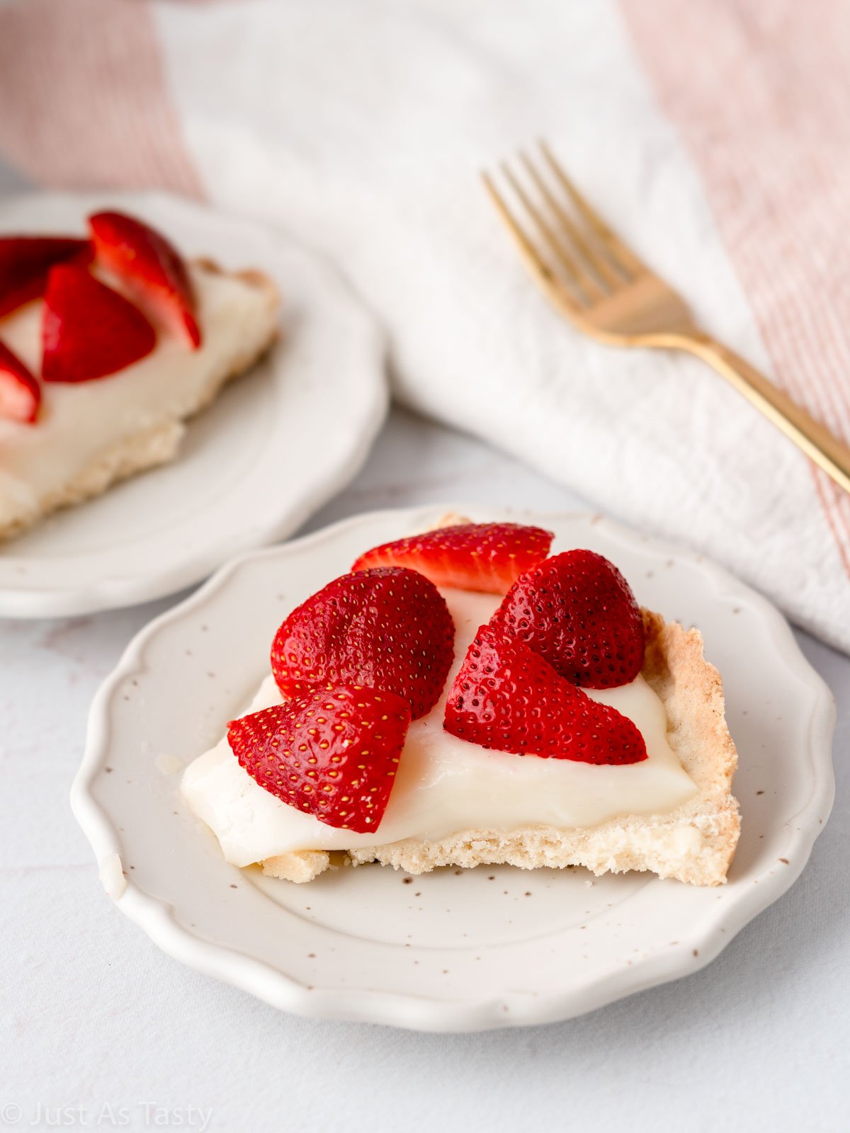 Slice of strawberry custard tart on a white plate. 