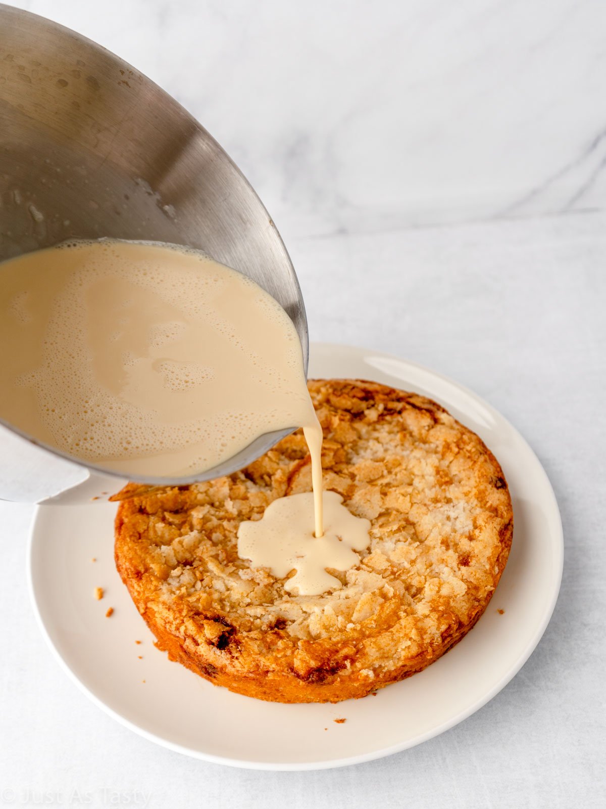 Action shot of three milk mixture being poured onto cake. 