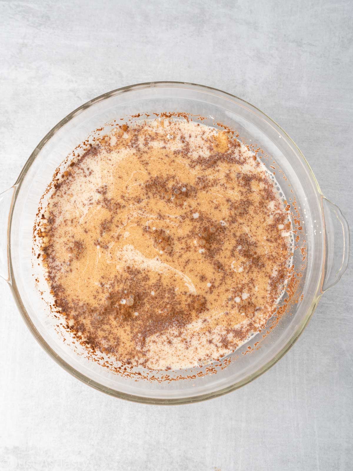 Milk and cinnamon mixture in a glass dish.