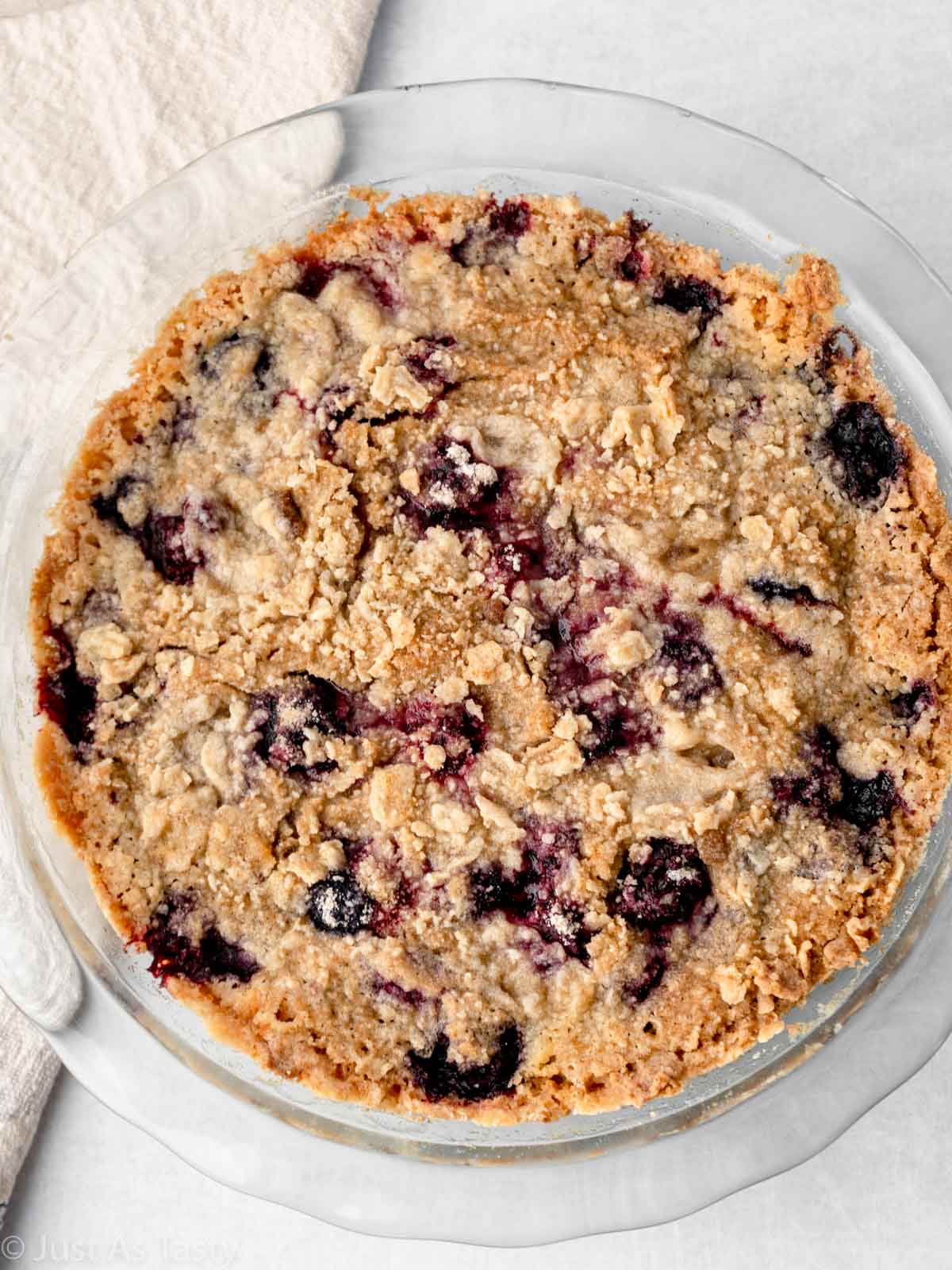 Blackberry pie with crumble topping in a glass pie plate.