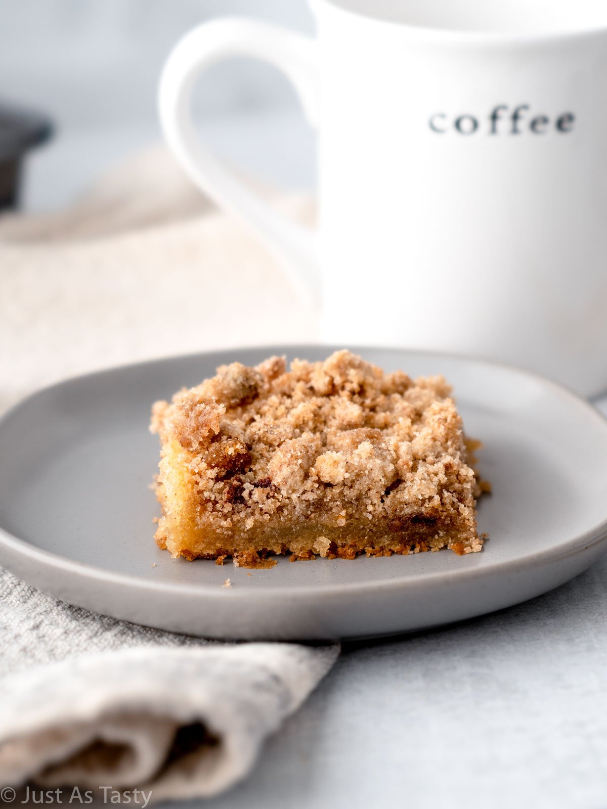 Slice of eggless coffee cake with streusel topping on a grey plate.