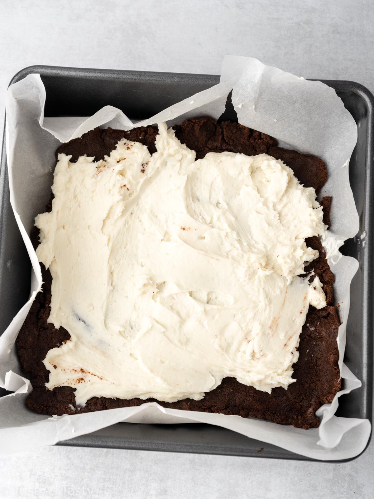 Brownie batter and cream cheese layer in a pan.