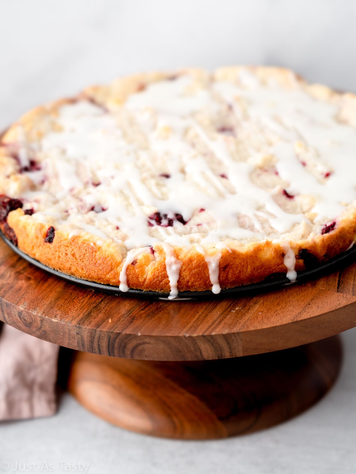 Close-up of glazed raspberry ricotta cake on a stand.
