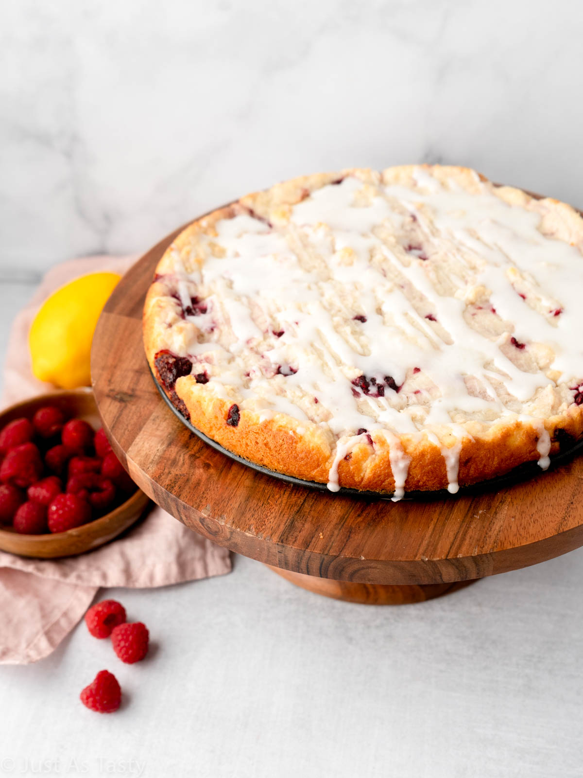 Raspberry ricotta cake with lemon glaze on a cake stand.