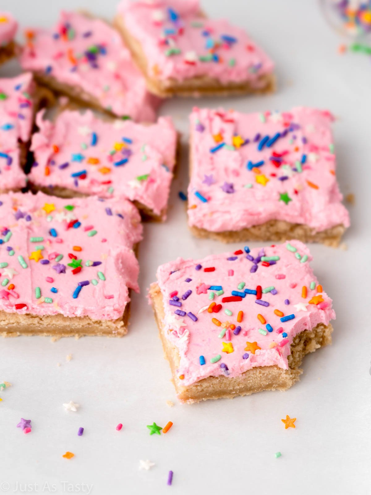Pink frosted sugar cookie bar with a bite taken out of it.