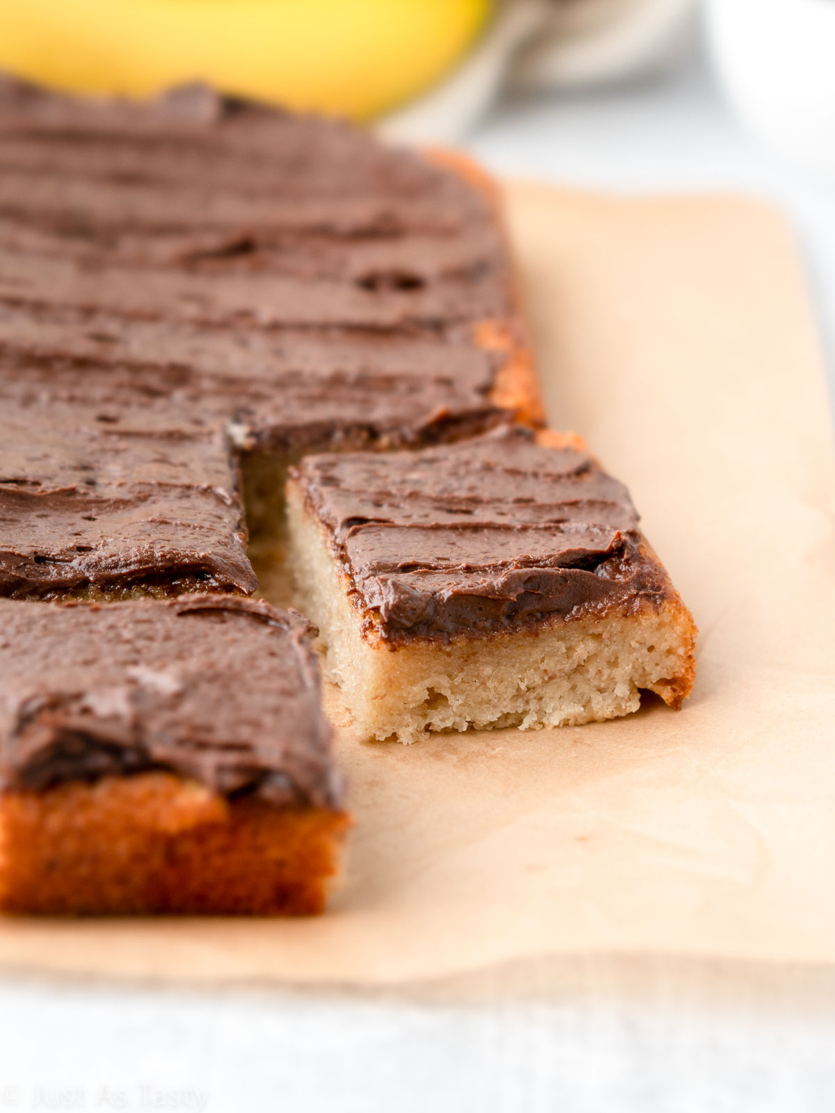 Close-up of a slice of banana cake topped with chocolate frosting. 