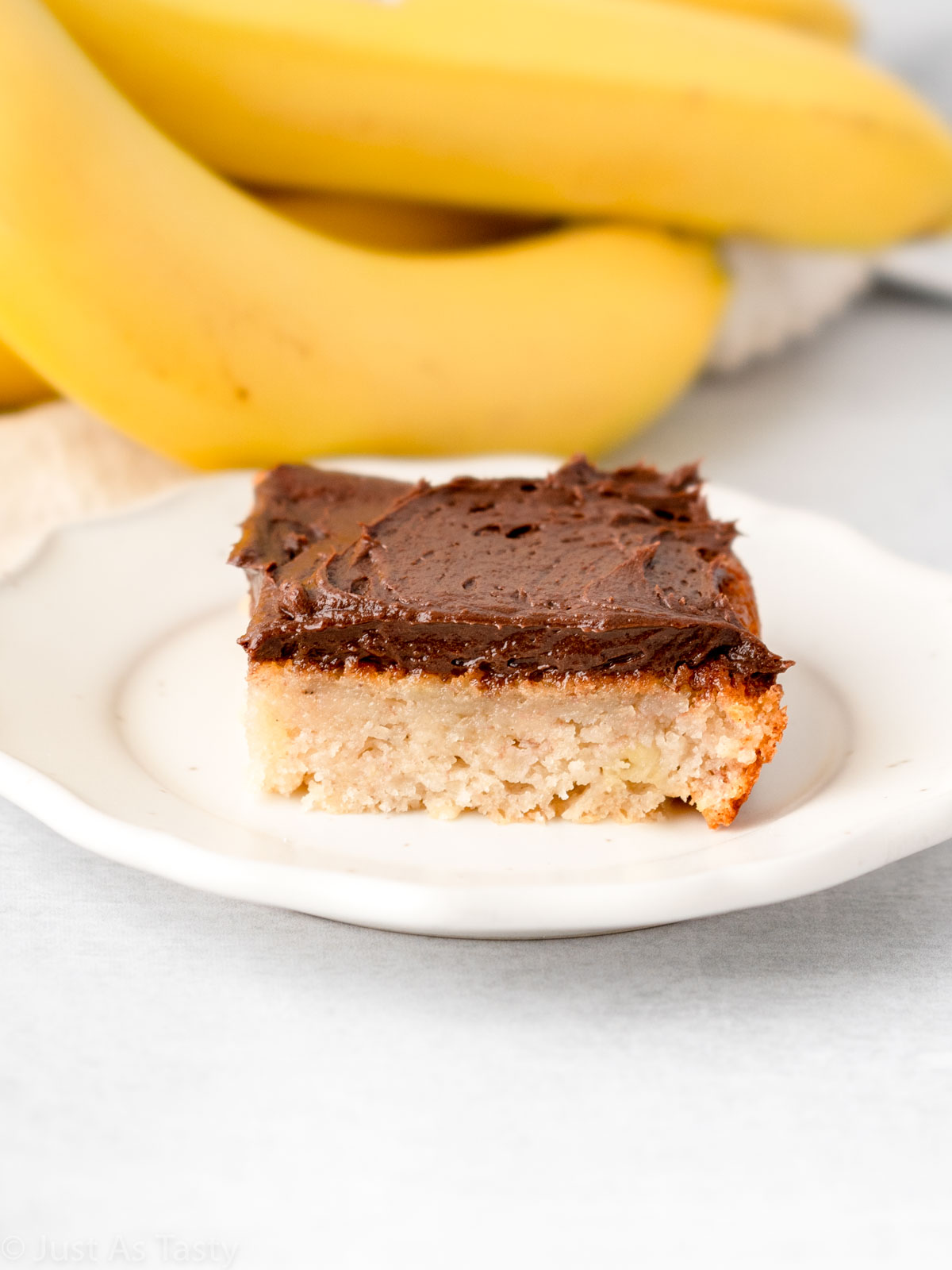 Slice of gluten free banana cake topped with chocolate frosting.