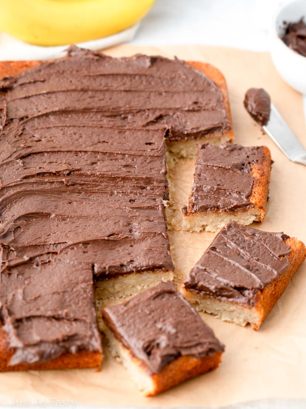 Sliced banana cake topped with chocolate frosting.