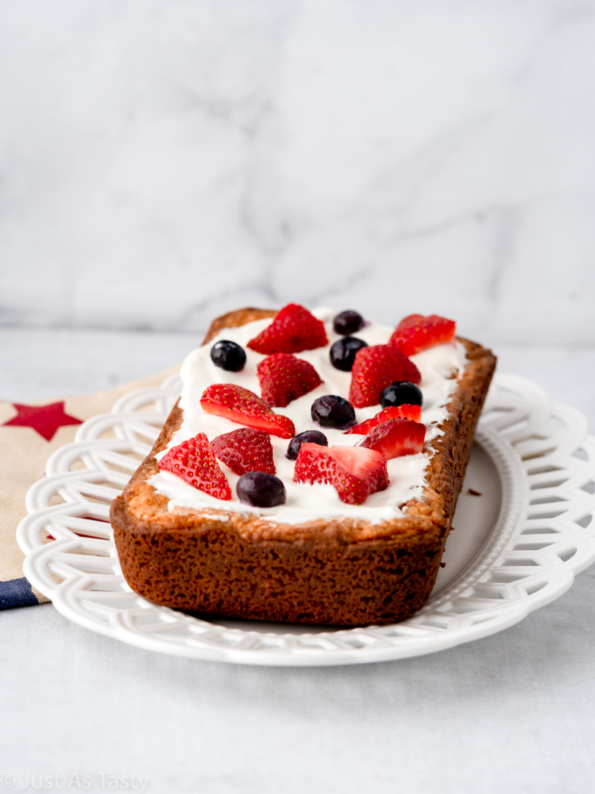 Gluten free loaf cake topped with whipped cream and berries. 