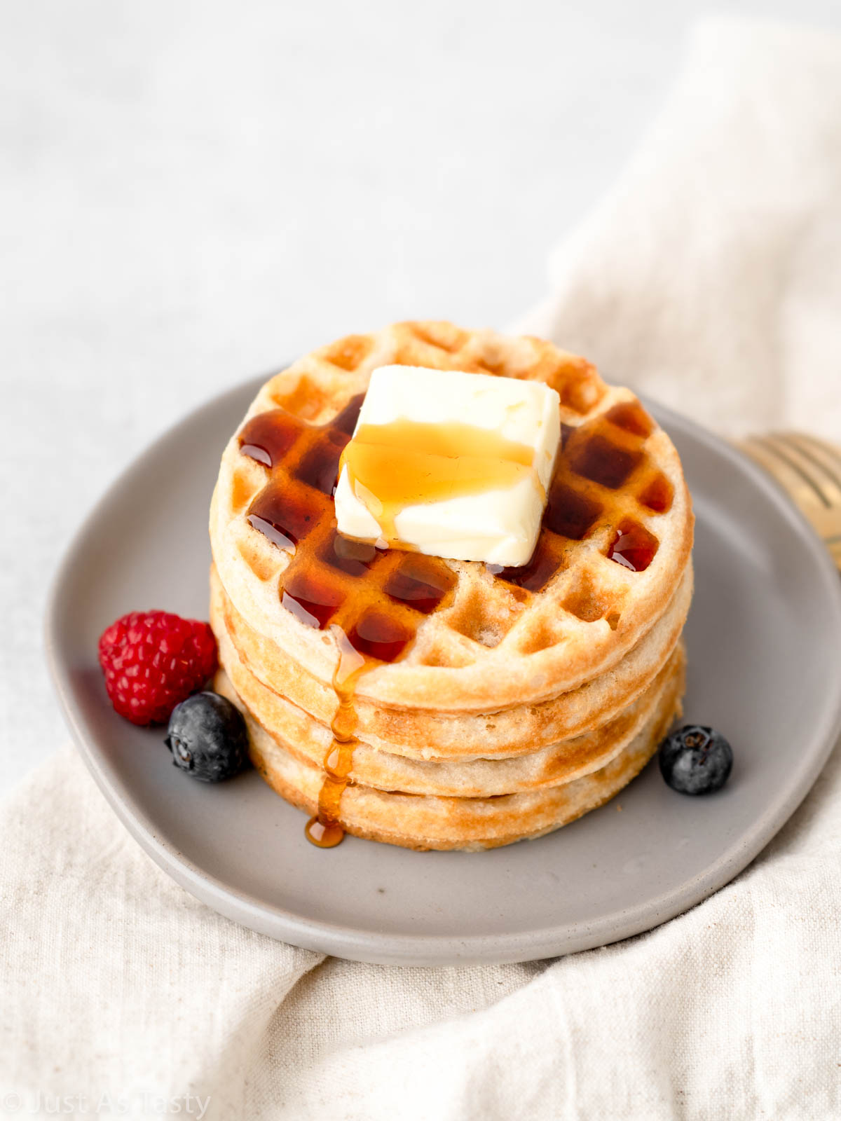 Gluten free waffles on a plate with butter and syrup. 