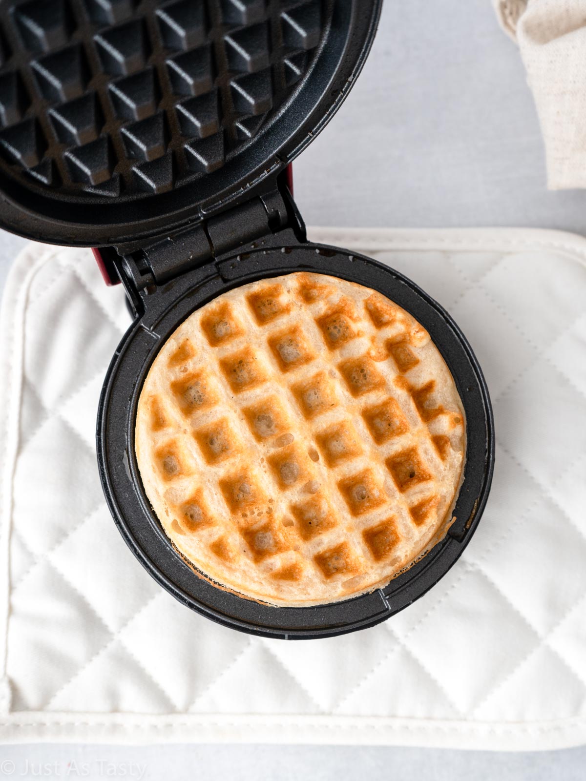Cooked waffle in a waffle iron.