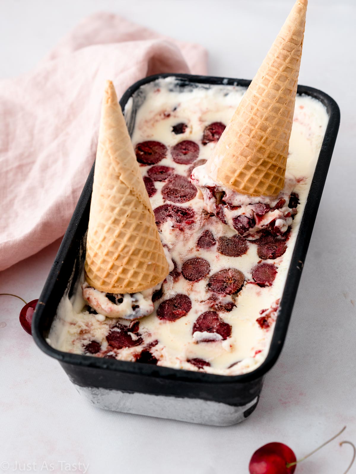 Black forest ice cream in a loaf pan with two sugar cones on top.