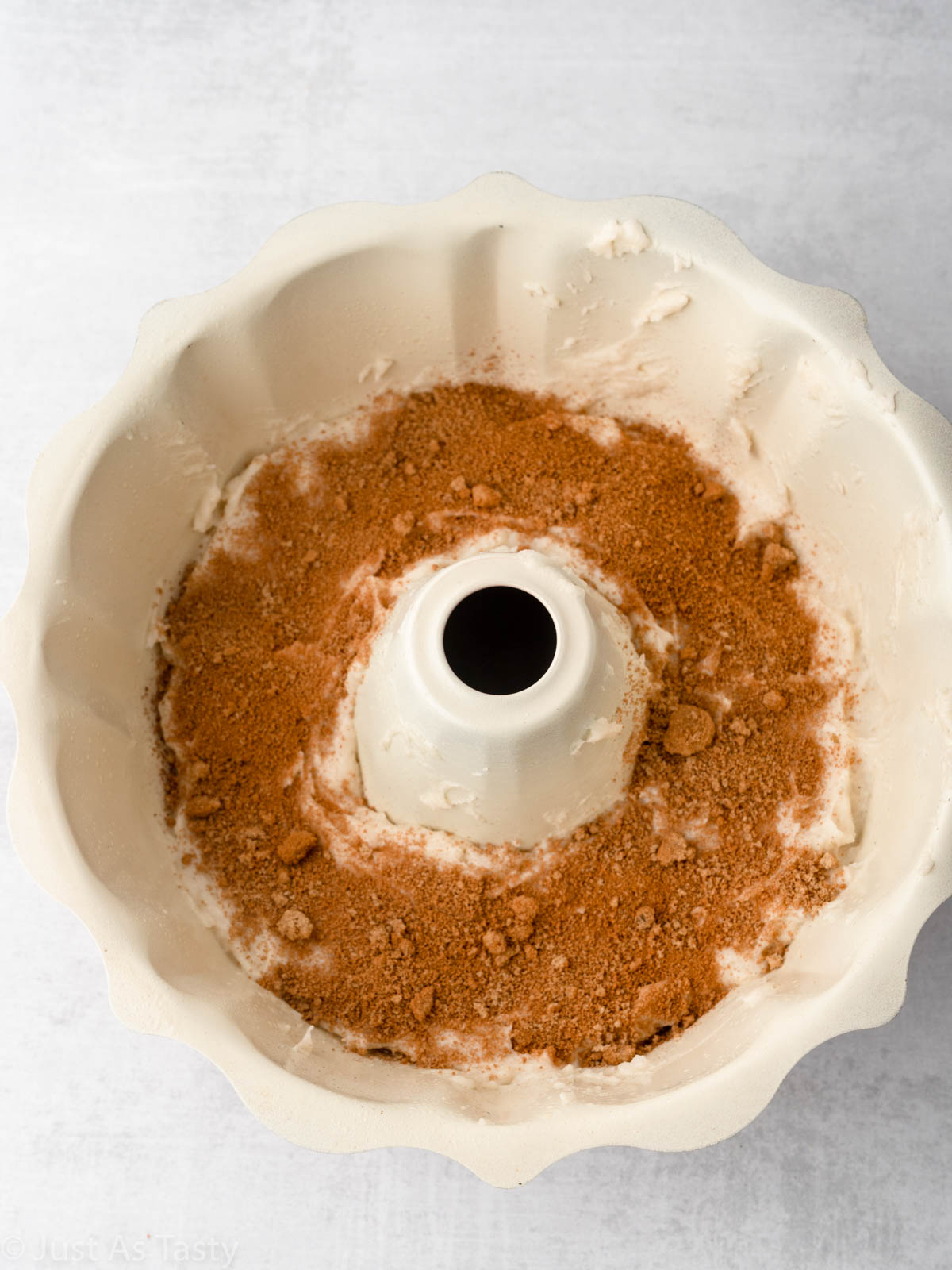 Cake batter topped with cinnamon sugar in a bundt pan.