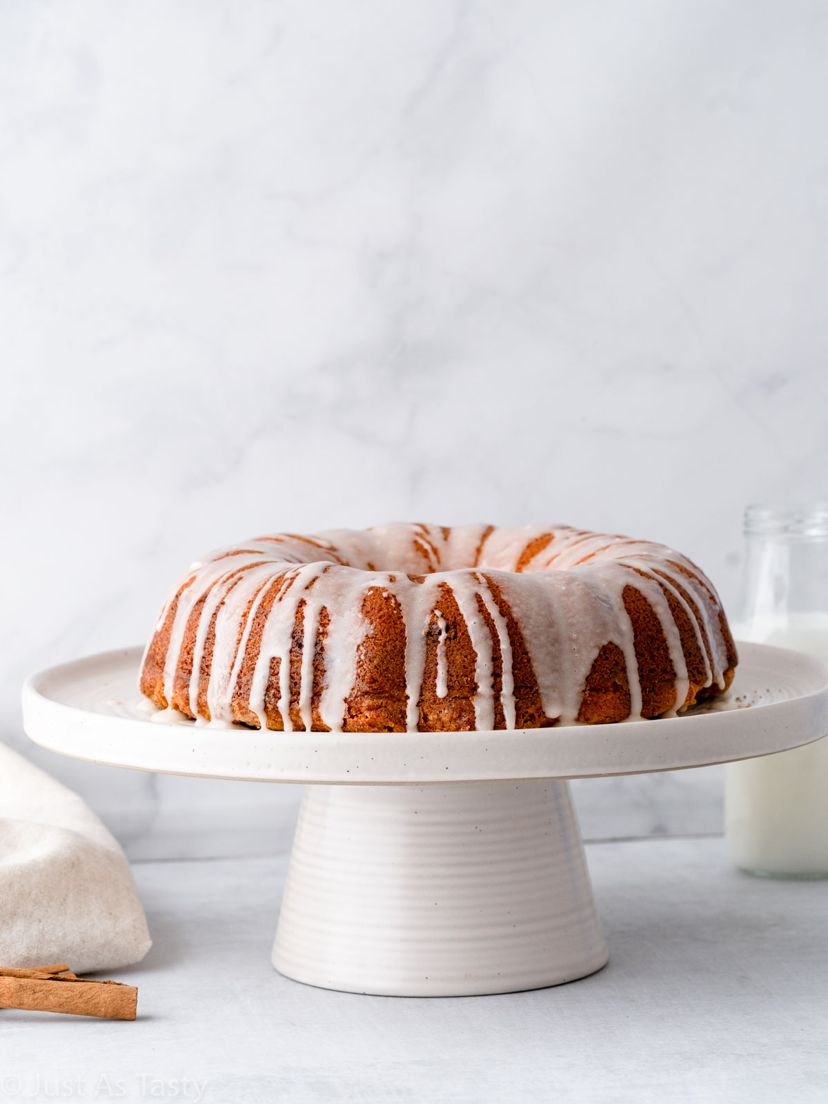 Glazed cinnamon roll bundt cake on a stand.