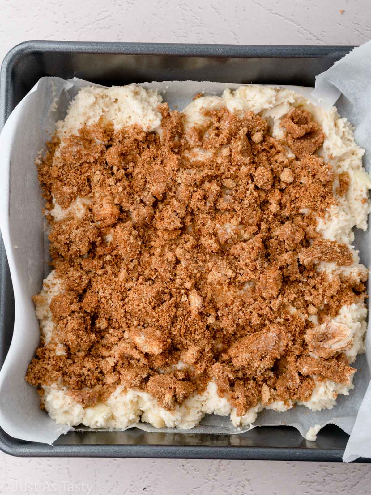 Cake batter topped with cinnamon topping in a square pan.