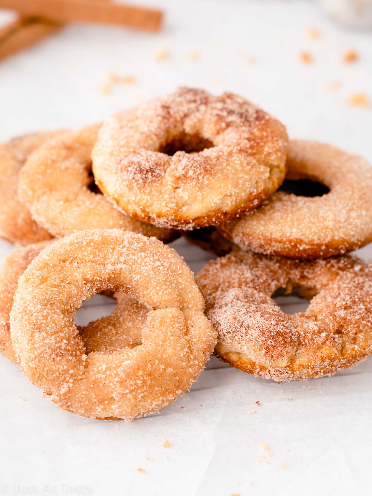 Stack of gluten free apple cider donuts topped with cinnamon sugar.