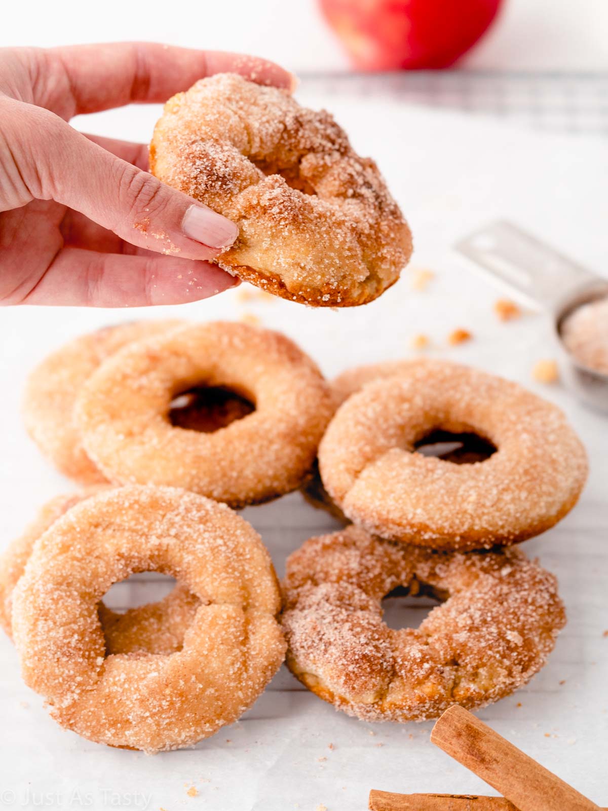 A hand picking up an apple cider donut. 