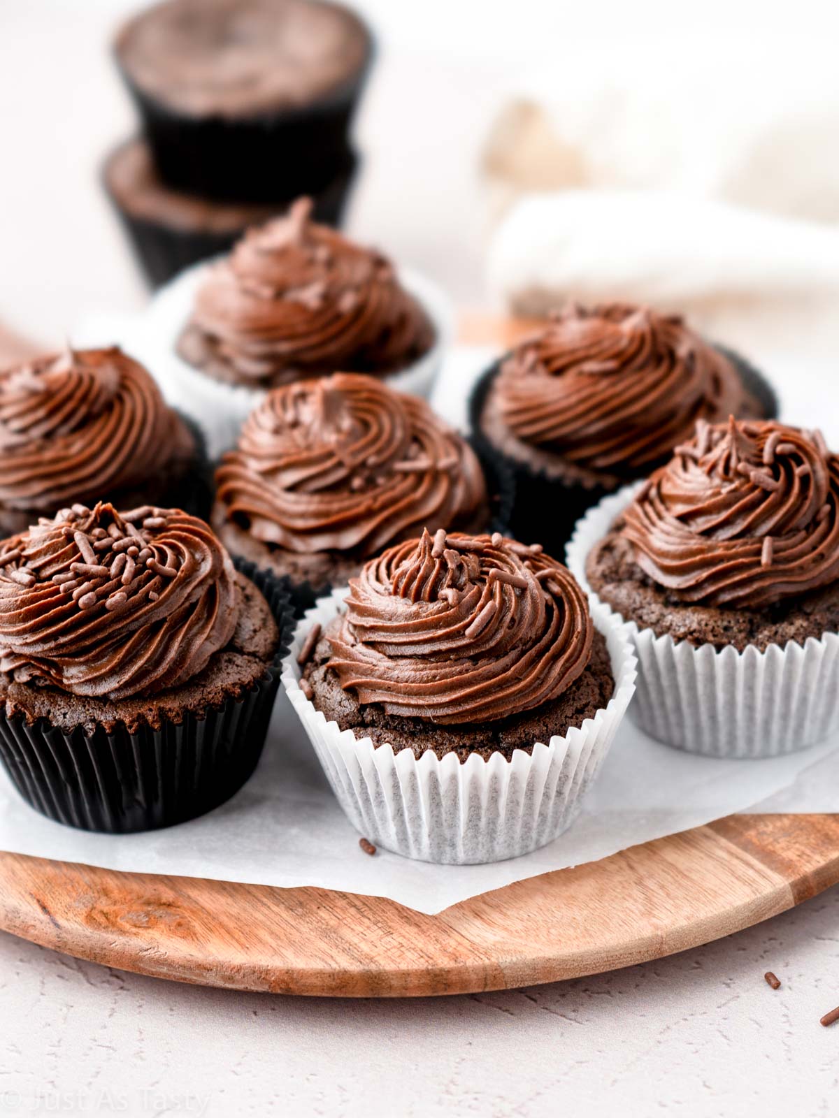 Frosted chocolate cupcakes on a round serving tray.