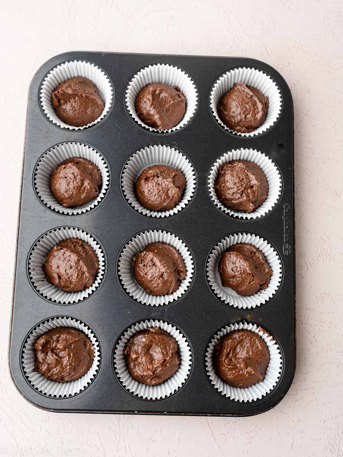 Chocolate cupcake batter in muffin tin.