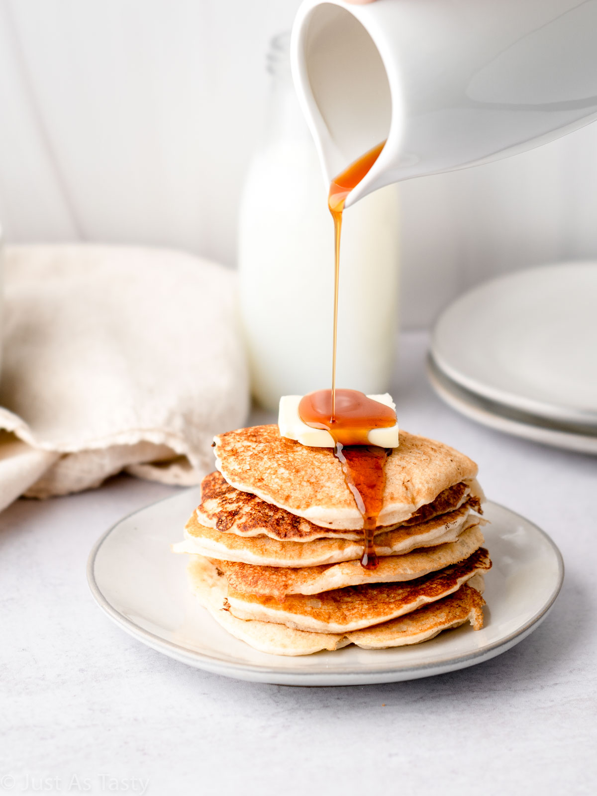 Stack of gluten free pancakes with syrup being poured on top.