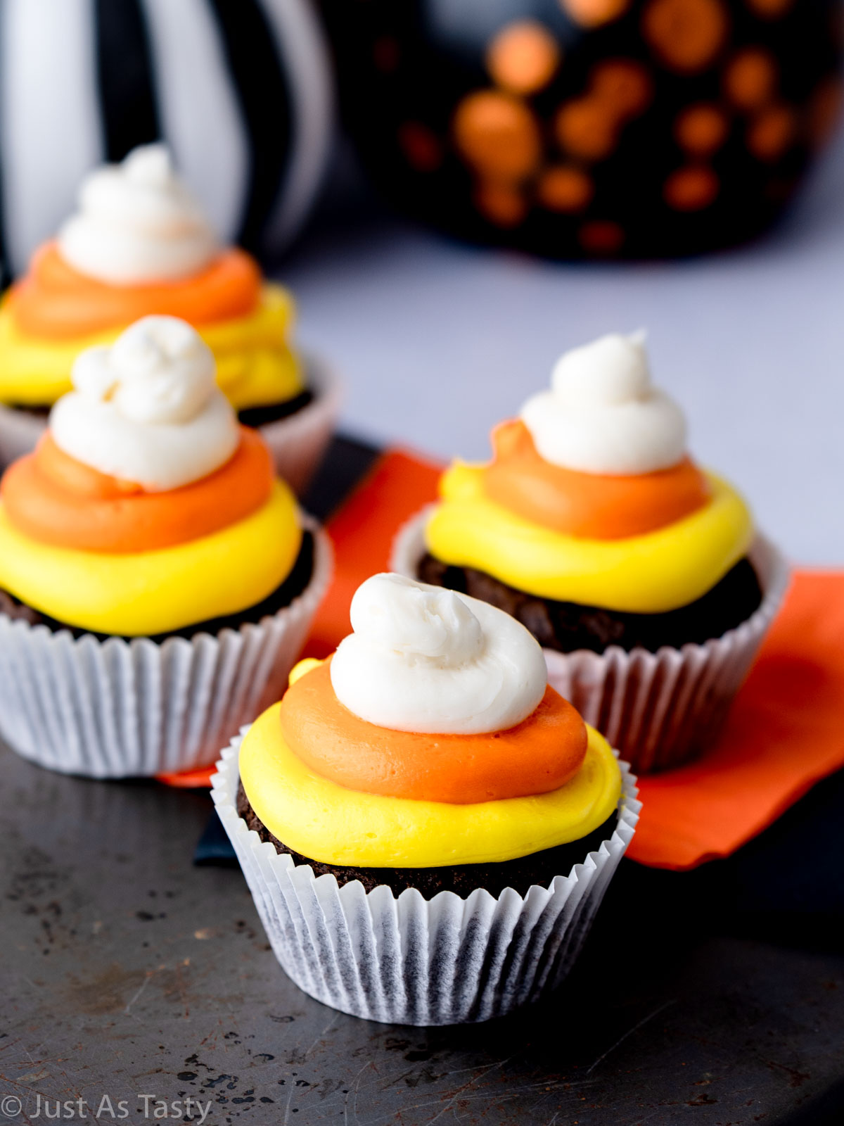 Chocolate cupcakes topped with yellow, orange, and white frosting. 