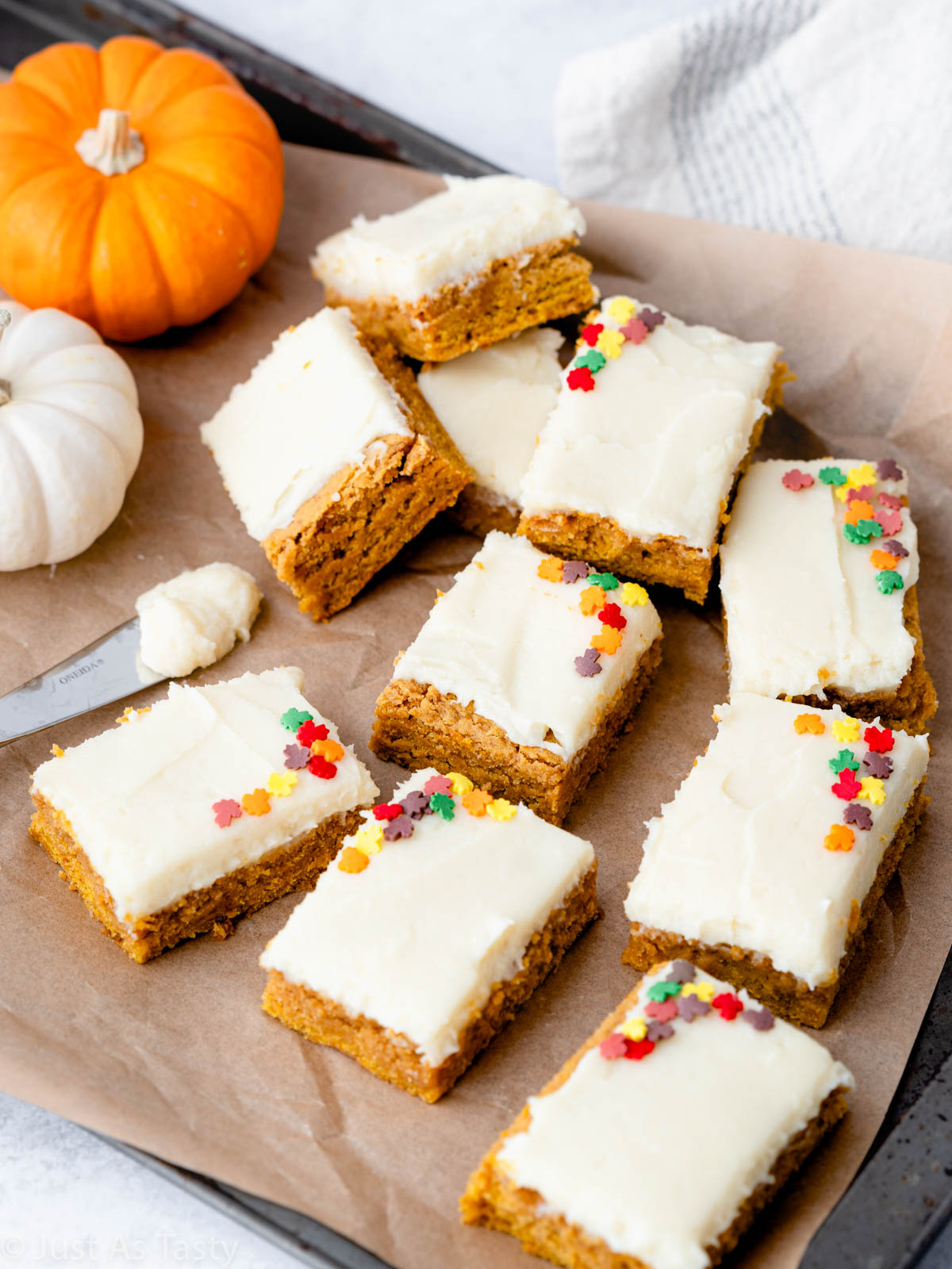 Frosted pumpkin bars on brown parchment paper.