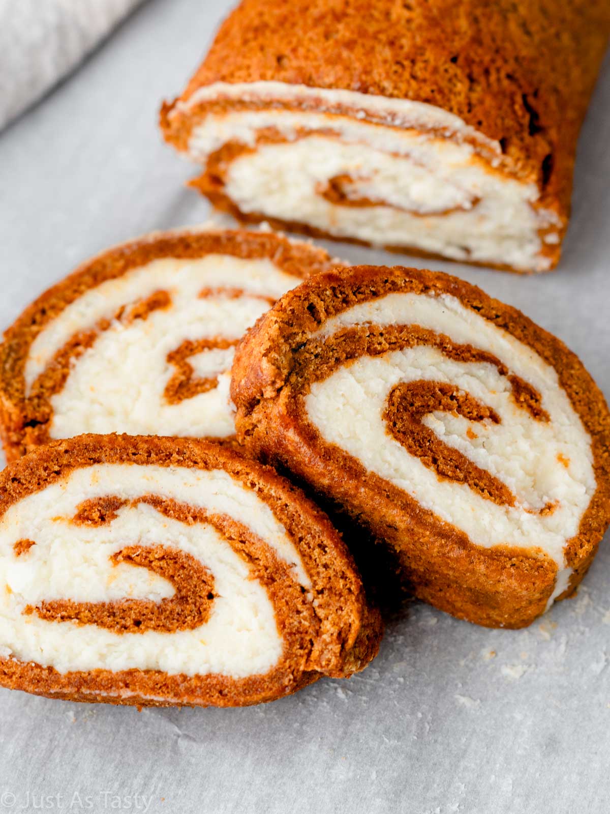 Three slices of pumpkin roll with cream cheese swirl filling.