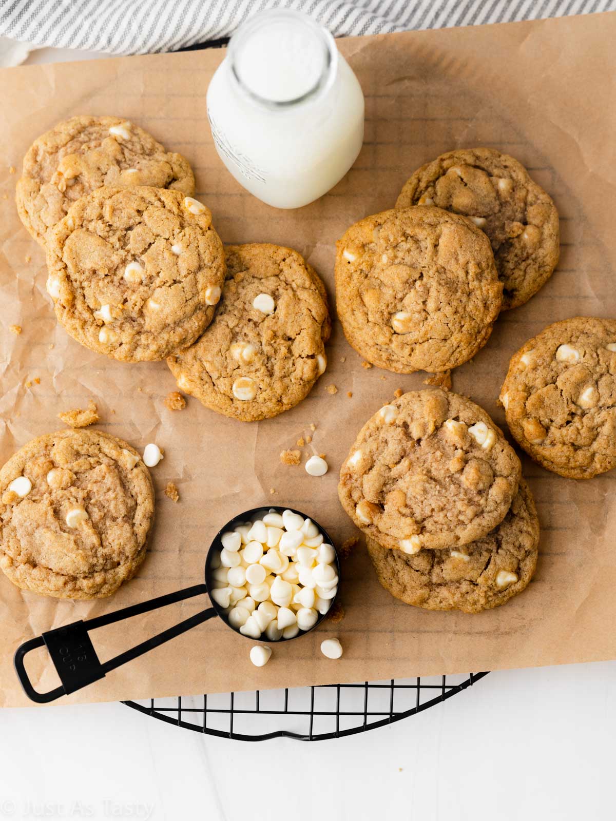 Apple pie cookies on brown parchment with a glass of milk and white chocolate chips. 